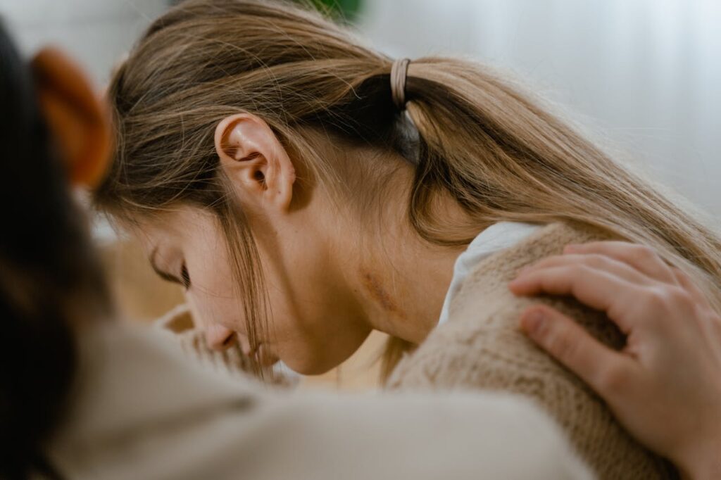 An emotional moment showing a comforting gesture with a hand on a woman's shoulder.